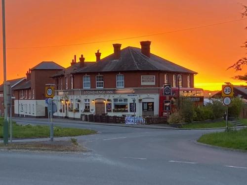 埃姆斯伯里Stonehenge Inn & Shepherd's Huts的街道边的建筑,享有日落美景