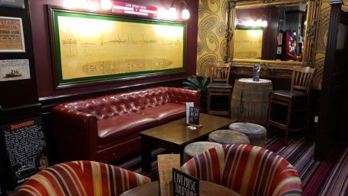 南安普敦The Grapes Pub的酒吧配有皮沙发、桌子和椅子