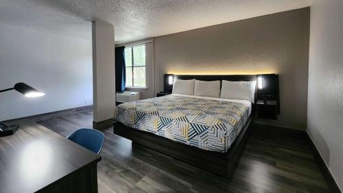 休斯顿Motel 6 Houston, TX - Medical Center - NRG Stadium的一间卧室配有一张床、一张桌子和一把椅子
