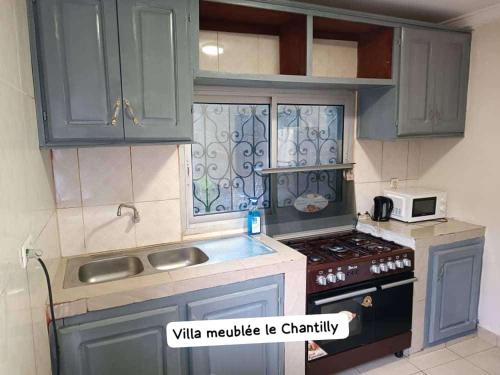 雅温得Dany Chantilly的一间小厨房,内配蓝色橱柜和微波炉