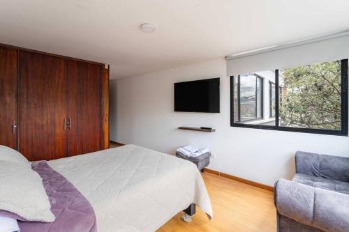 波哥大Enorme Casa Campestre en Bogotá的一间卧室配有一张床、一台电视和一把椅子