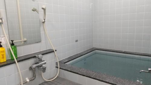 Inaiビジネスホテルパークイン石巻的浴室内配有带软管的浴缸