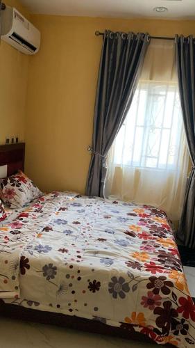 伊洛林SHORT Rental的一间卧室配有一张带花卉棉被的床和窗户。