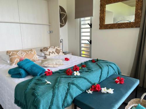 乌图罗阿La Suite Vue Lagon的一张床上有蓝色的毯子和红色的鲜花