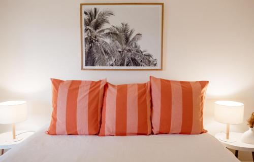 仙女港Banksia Beach House的一间卧室配有带两个橙色和白色枕头的床