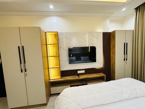 焦特布尔MG apartments的一间卧室配有一张床和一台平面电视