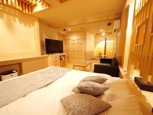 姬路ホテル カーシュ Cache 男塾ホテルグループ的卧室配有一张带三个枕头的大型白色床