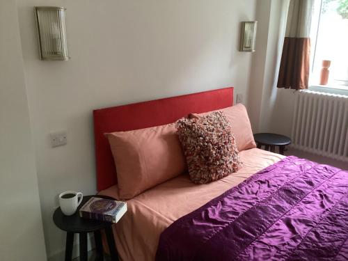 灵伍德Forest Heath Holidays - The Nook的一张带红色床头板和枕头的床