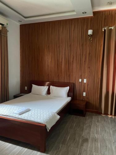 海阳Trúc Lâm hotel的一间卧室配有一张带木墙的大床
