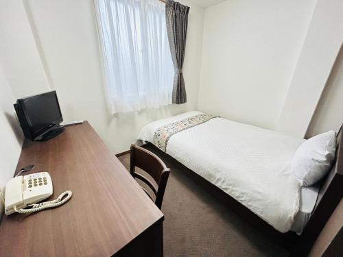 会津若松グリーンホテル会津的客房设有一张床、一张书桌和一部电话