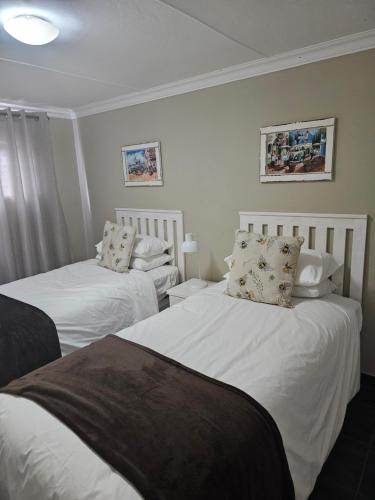 昆斯敦Amberdale Estate Self Catering的配有2张床的带白色床单和枕头的客房
