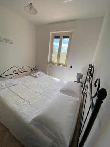 托里德欧索Villa Laurus的一间卧室配有一张带白色床单的床和一扇窗户。