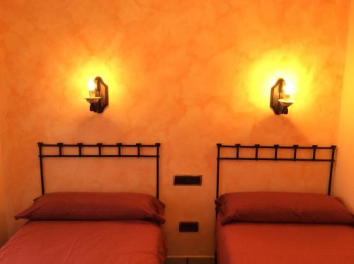 SedilesCasa Rural Sierra Vicor的墙上灯的房间里设有两张床