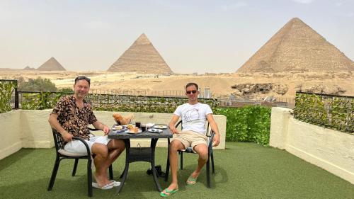 开罗Solima pyramids inn的两个坐在金字塔前桌边的人