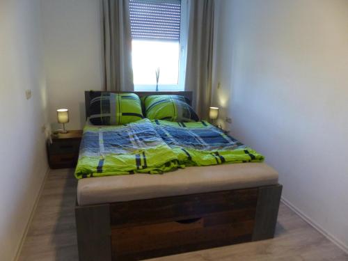 霍夫Ferienwohnung in Hof Saale的一间卧室配有一张带绿色棉被的床和窗户。