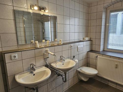 金茨堡Hotel Hirsch Günzburg的浴室设有2个水槽、卫生间和镜子。