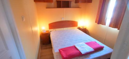 Biaslocationestivale40 Bungalow petit budget océan forêt的一间小卧室,配有一张带两个粉红色枕头的床