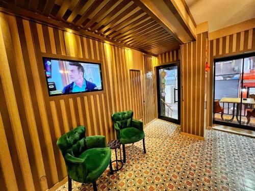伊斯坦布尔Taksim Cetinkaya Suite的一间设有绿色椅子和墙上电视的房间