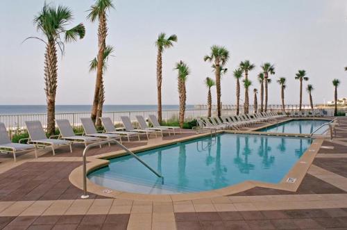 巴拿马城海滩Sterling Reef Beach Resort的海滩旁的游泳池设有椅子和棕榈树