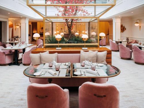 巴黎Sofitel Le Scribe Paris Opera的一间设有粉红色椅子和桌子的餐厅