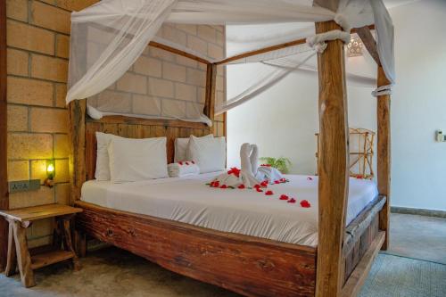 南威Maisha Nungwi的一间卧室配有一张带红色弓的天蓬床