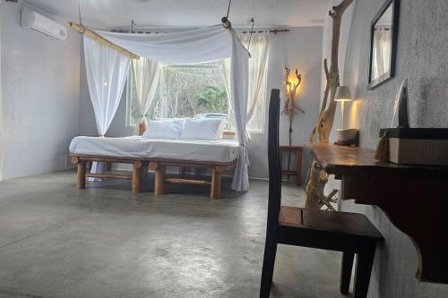 拉克鲁斯Villa Ballena Art Project的一间卧室配有一张带天蓬和窗户的床