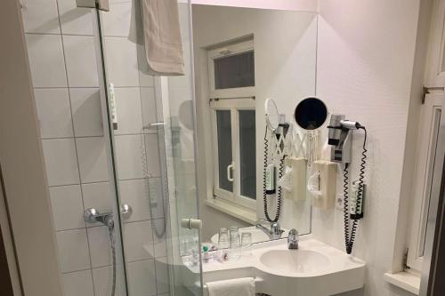施韦比施哈尔Aspire Kronprinz, Trademark Collection by Wyndham的浴室配有盥洗盆、淋浴和电话