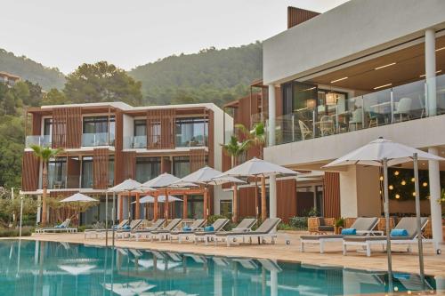 圣米格尔港The Club Cala San Miguel Hotel Ibiza, Curio Collection by Hilton, Adults only的酒店设有带椅子和遮阳伞的游泳池