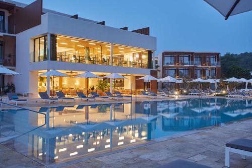 圣米格尔港The Club Cala San Miguel Hotel Ibiza, Curio Collection by Hilton, Adults only的酒店设有带椅子和遮阳伞的游泳池