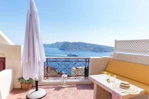 伊亚Beautiful Oia Villa - Spectacular Sea Views - Sunset & Caldera Views - Aegean Serenity Villa的阳台配有黄色沙发和雨伞。