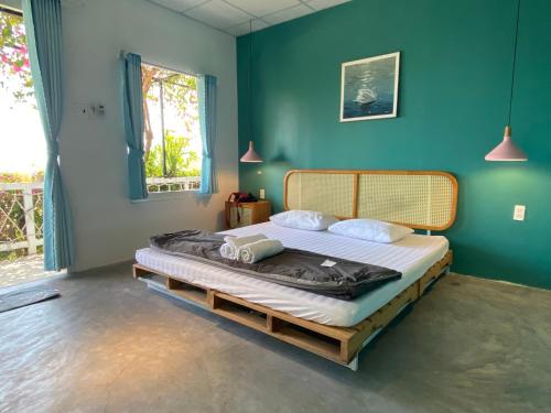 绥和市Kaktus home & kafe的一间卧室,在蓝色的墙壁上配有一张大床
