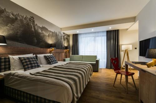 什恰夫尼察Szczawnica Park Resort & Spa的酒店客房设有一张大床和一张书桌。