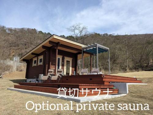 山中湖村Log cabin rental & Finland sauna Step House的小屋设有门廊和田野椅子