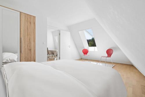 洛桑Boissonnet 96 Residence by Homenhancement的一间卧室配有白色的床和两张红色椅子