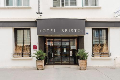 凯恩L'Hôtel Bristol的一间酒店前面的英国商店,里面装有盆栽植物