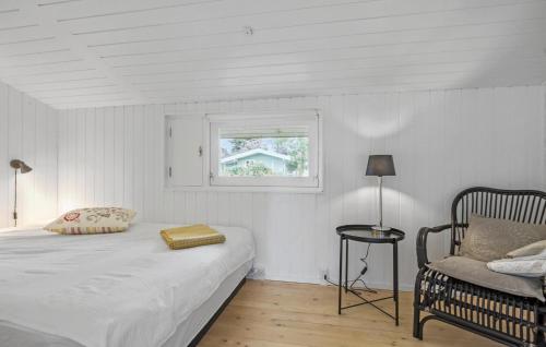 吉利勒杰3 Bedroom Cozy Home In Gilleleje的一间卧室设有一张床、一个窗口和一把椅子