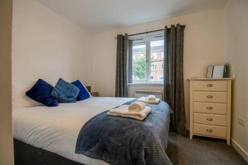佩斯利2 bed flat near airport &parking的一间卧室配有一张带蓝色枕头的床和一扇窗户。