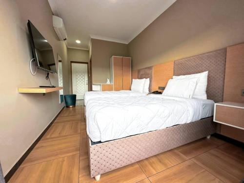 基加利acacus hotel的一间卧室配有一张大床和电视