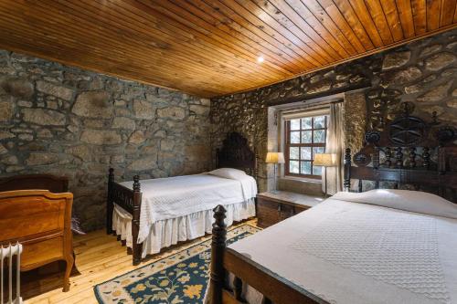 布拉加Casa da Pedra Cavalgada的一间卧室设有两张床和石墙