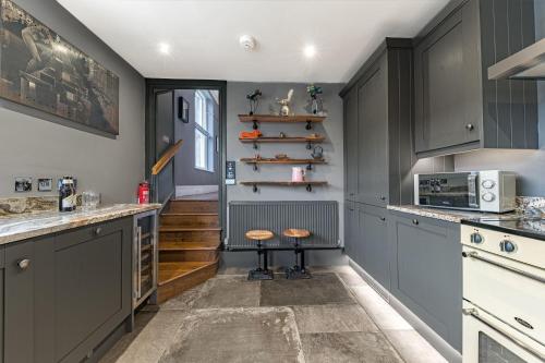 凯西克The Eyrie的厨房配有灰色橱柜和带凳子的台面