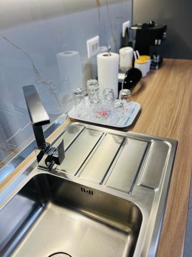 地拉那ALBI’S Apartment的厨房配有水槽和带玻璃杯的台面