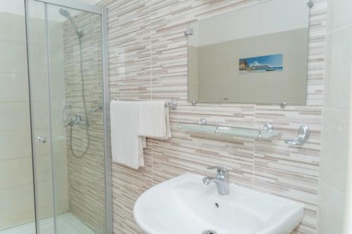 科纳克里Hotel Azur Conakry的一间带水槽、淋浴和镜子的浴室