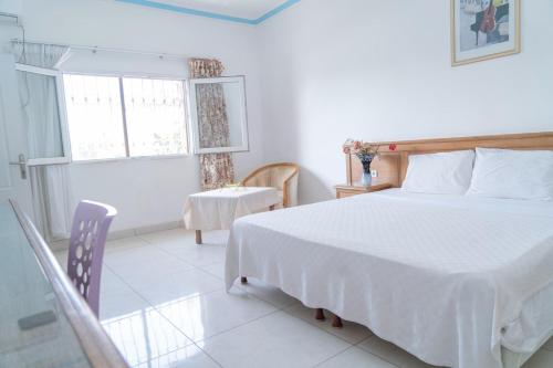 科纳克里Hotel Azur Conakry的一间卧室配有一张床、一张桌子和一个窗户。
