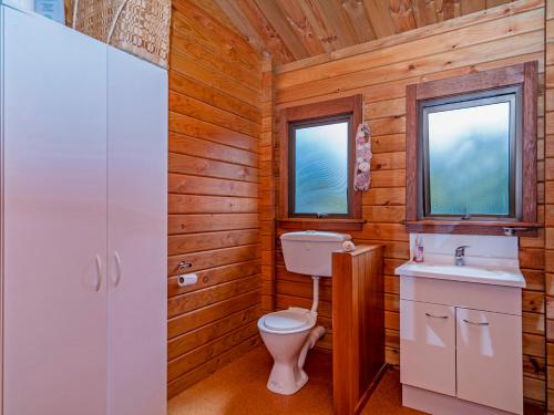 WhangapouaBoltons Bach - Whangapoua Bach的一间带卫生间和水槽的浴室以及两个窗户。