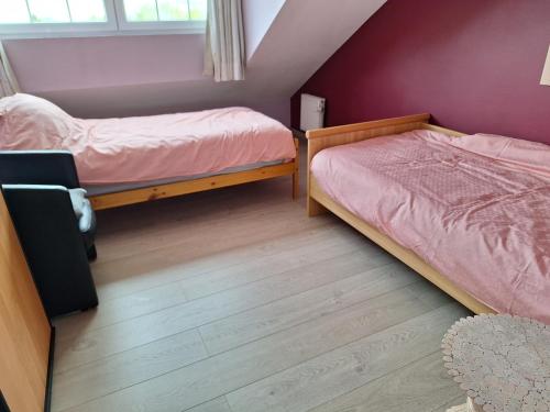 赫林贝亨Kapstertje的配有紫色墙壁和木地板的客房内的两张床