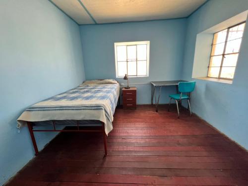 豪哈Casa Rosita Sausa的一间卧室配有一张床、一张书桌和两个窗户。