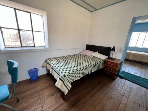 豪哈Casa Rosita Sausa的一间卧室配有一张床、一个梳妆台和两个窗户。