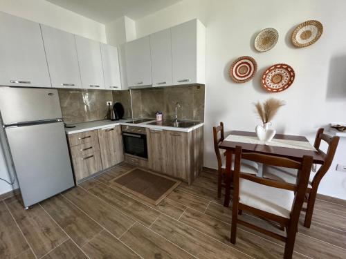 圣金Sunset Serenity的厨房配有白色橱柜、桌子和冰箱。