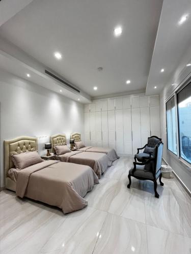 吉达شقة مريحة فاخرة Cozy apartment, luxury with fun的一间卧室设有三张床、一把椅子和一个窗户。