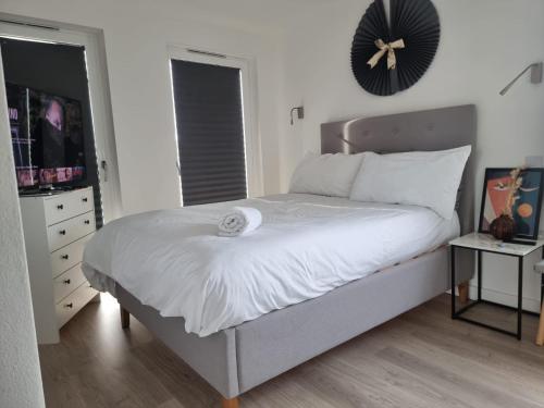 Elmers EndBeckenham- PRIVATE DOUBLE Bedroom With En-suite in SHARED APARTMENT的卧室配有一张挂在墙上的带时钟的床